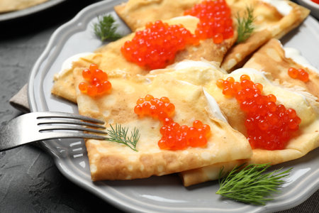 Tasty crepes with red caviar and sour cream on black table, closeupの写真素材
