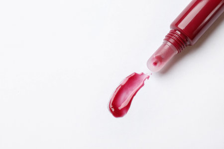 Beautiful dark red lip gloss with swatch on white background, top view. Space for textの写真素材