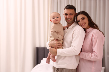 Happy parents with their cute baby at home. Space for textの写真素材