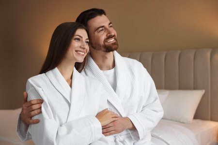 Happy couple in bathrobes on bed indoorsの写真素材