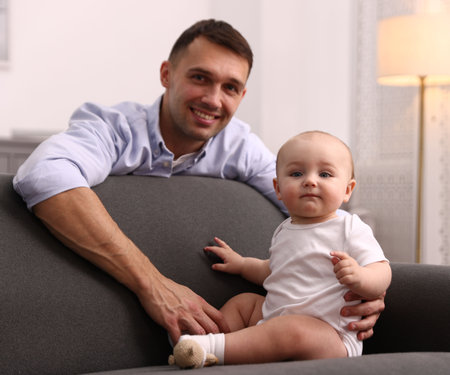 Happy father with his cute baby on sofa at home, selective focusの写真素材