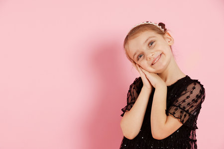 Smiling little girl in headband on pink background. Space for textの写真素材
