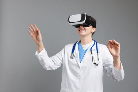 Modern technology. Doctor in headset using virtual screen on gray backgroundの写真素材