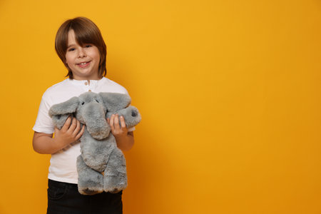 Boy with toy elephant on yellow background. Space for textの写真素材