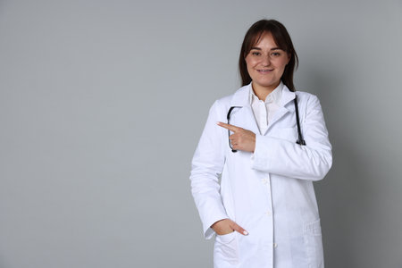 Doctor in medical uniform with stethoscope on gray background, space for textの写真素材
