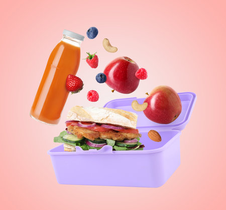 Lunch box, food and drink flying in air on pink backgroundの写真素材