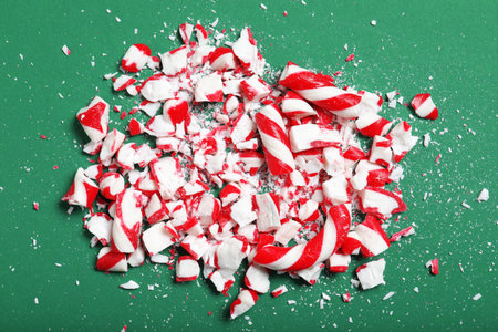 Pile of crushed candy canes on green background, flat lay. Christmas treatの写真素材