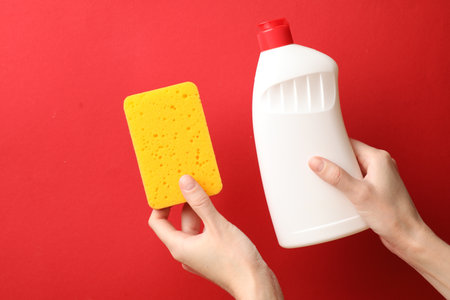 Woman holding sponge and dish soap on red background, top viewの写真素材