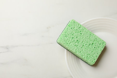 Kitchen sponge and plate on white marble table, top view. Space for textの写真素材