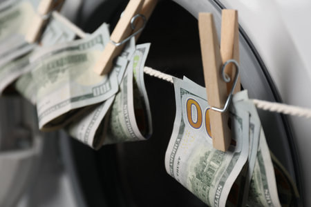 Banknotes hanging on clothesline near washing machine, closeupの写真素材