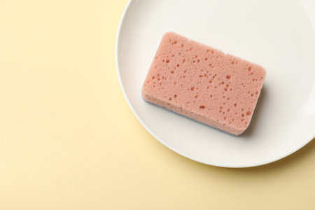 Kitchen sponge and plate on beige background, top view. Space for textの写真素材