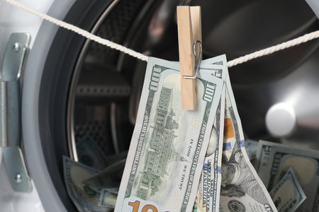 Banknotes hanging on clothesline near washing machine, closeupの写真素材