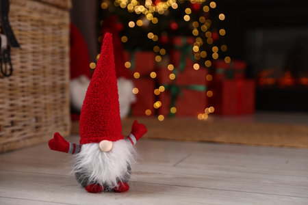 Funny Christmas gnome on floor in decorated room. Space for textの写真素材