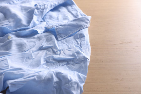 Light blue creased shirt on wooden table, closeup. Space for textの写真素材
