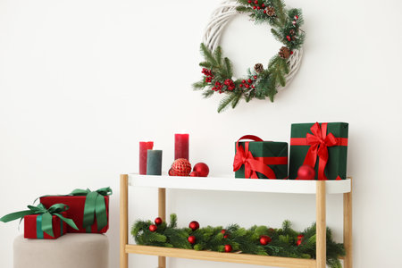 Christmas decor and burning candles on console table near white wall indoors. Interior designの写真素材