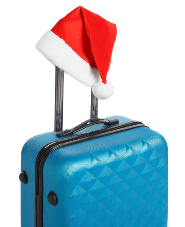 Christmas vacation. Blue suitcase with Santa hat on white backgroundの写真素材