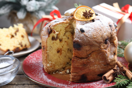 Tasty Christmas panettone cake with powdered sugar and festive decor on wooden table, closeupの写真素材