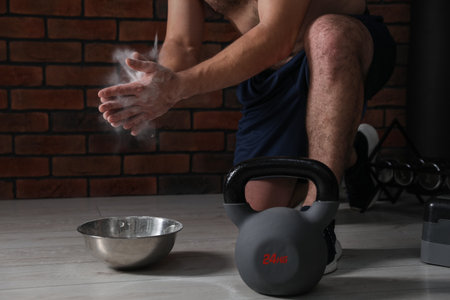 Man applying talcum powder on hands before training with kettlebell in gym, closeupの写真素材