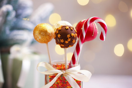 Sweet cake pops, sprinkles and candy canes against Christmas lights, closeup. Bokeh effectの写真素材