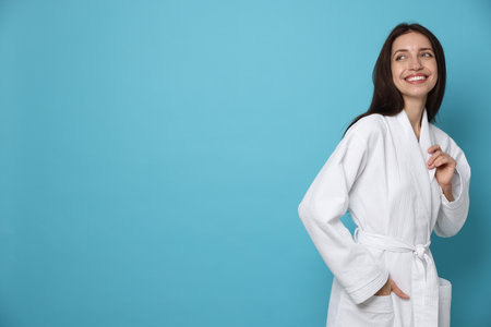 Woman wearing bathrobe on light blue background. Space for textの写真素材