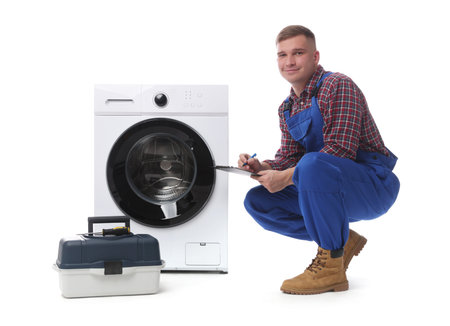 Repairman in uniform with pen, clipboard, toolbox and washing machine on white backgroundの写真素材