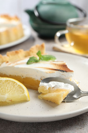 Slice of tasty lemon meringue tart with mint served on light gray table, closeupの写真素材