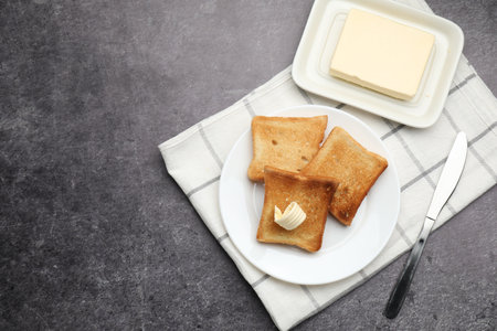 Fresh toasted bread slices with butter on gray table, flat lay. Space for textの写真素材