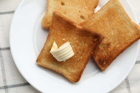 Fresh toasted bread slices with butter on table, top view