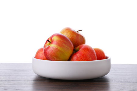 Ripe red apples in bowl on wooden table against white background, closeupの写真素材