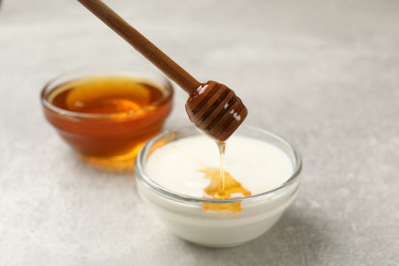Dripping honey into Greek yogurt at light gray table, closeupの写真素材