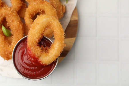 Deep fried squid rings on white tiled table, top view. Space for text