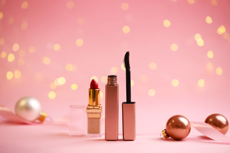 Makeup products and Christmas decor on pink background with blurred lights, bokeh effectの写真素材