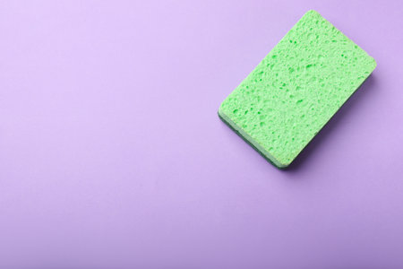 Kitchen sponge on violet background, top view. Space for textの写真素材