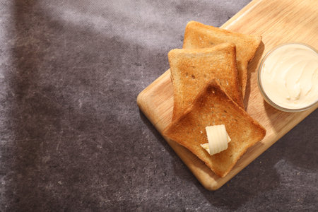 Fresh toasted bread slices with butter on gray table, top view. Space for text