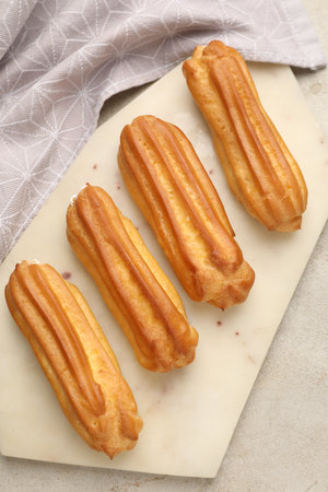 Fresh tasty eclairs on light table, top view