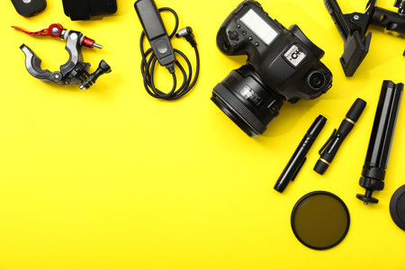 Professional photographer's equipment on yellow background, flat lay. Space for textの写真素材