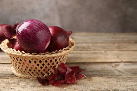Fresh onion bulbs and peels on wooden table, closeup. Space for textの写真素材