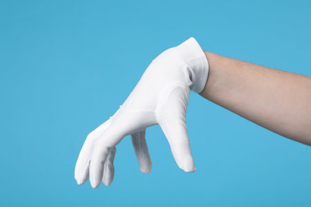 Woman in cloth glove on light blue background, closeup