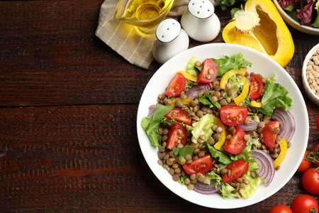 Delicious lentil salad and ingredients on wooden table, flat lay. Space for textの写真素材