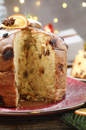 Tasty Christmas panettone cake with powdered sugar and festive decor on wooden table, closeupの写真素材