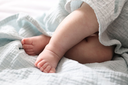 Cute newborn baby wrapped with blanket on bed indoors, closeupの写真素材
