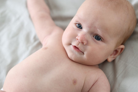 Cute newborn baby lying on bed, above view