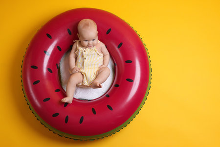Cute little baby on inflatable ring against orange background, top viewの写真素材