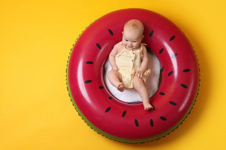 Cute little baby on inflatable ring against orange background, top viewの写真素材