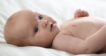 Cute newborn baby lying on bed indoorsの写真素材