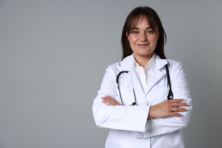 Doctor in medical uniform with stethoscope on gray background, space for textの写真素材