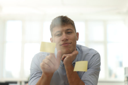 Man sticking note on glass board in office