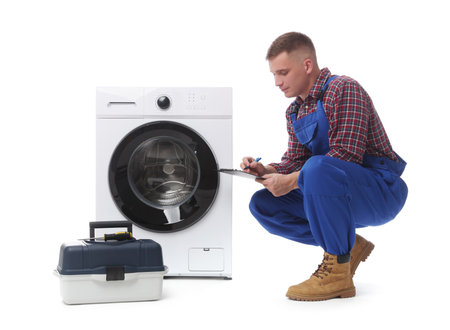 Repairman in uniform with pen, clipboard, toolbox and washing machine on white backgroundの写真素材