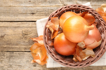 Fresh onion bulbs and peels on wooden table, top view. Space for textの写真素材