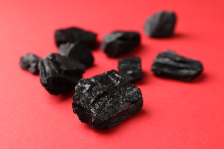 Pieces of black coal on red background, closeupの写真素材